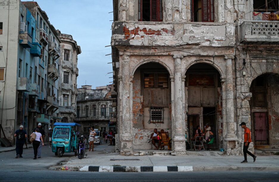 Havana street scene with people walking past crumbling buildings